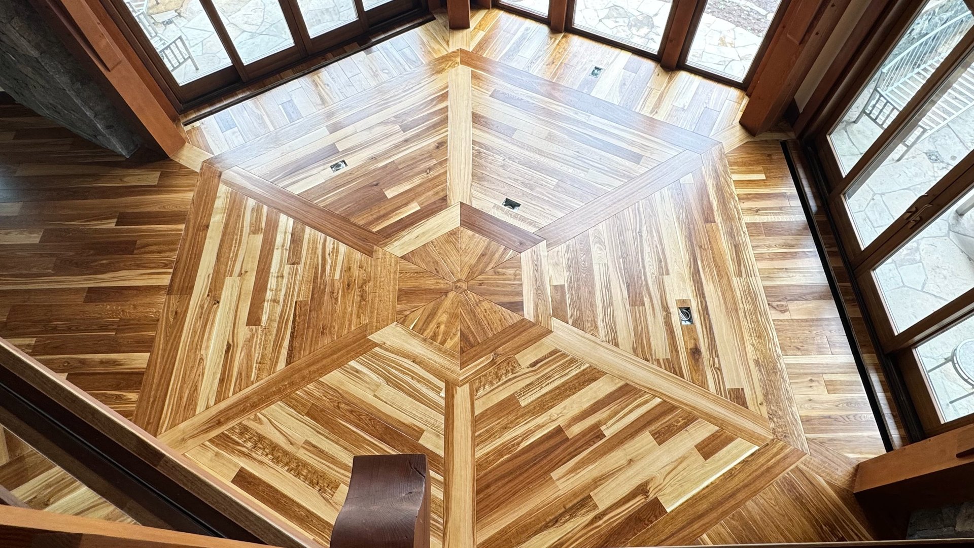 Wooden foyer with geometric parquet flooring pattern and skylight ceiling with natural lighting